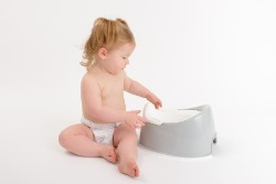 Toddler sitting next to plastic potty